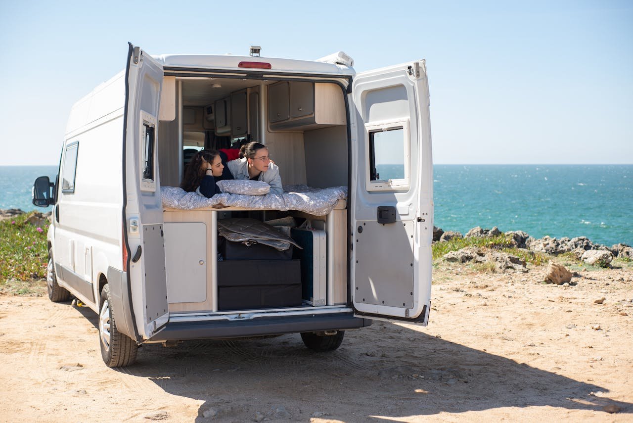 Ein Wohnmobil fährt durch die weite Landschaft Mecklenburg-Vorpommerns, im Hintergrund Seen und Wälder bei Sonnenuntergang – Symbol für Freiheit und Natur. Wohnmobil mieten in Mecklenburg-Vorpommern
