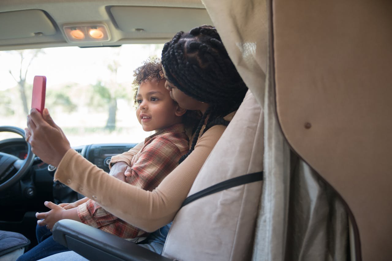 „Reisen mit Kindern mit dem Wohnmobil: Familie vor dem Wohnmobil auf dem Campingplatz“

