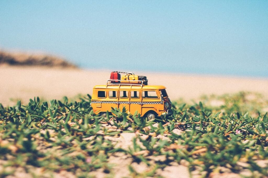 Ein gelber Spielzeug-Van auf grünem Seegras als Symbol für die Reise mit dem Wohnmobil.

