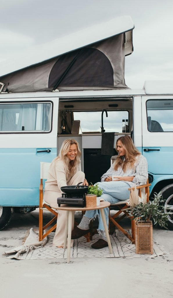 Ein stylisches VW-Wohnmobil mit zwei Frauen, die draußen entspannen