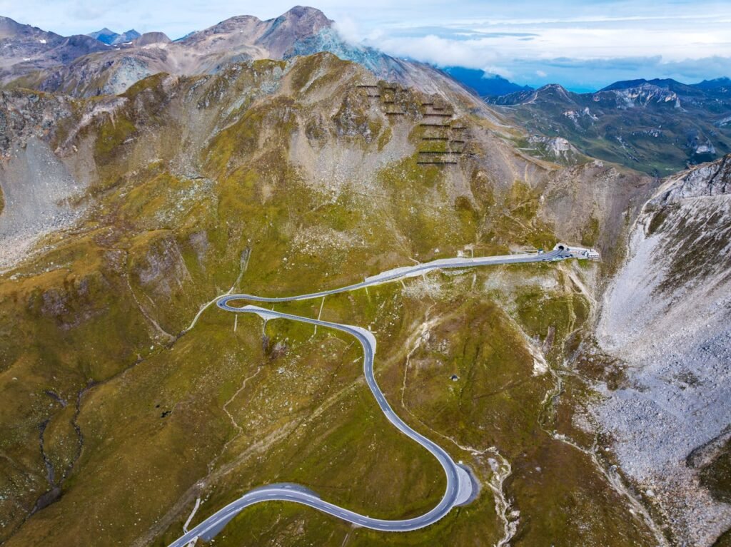 Spektakuläre Luftaufnahme einer kurvenreichen Bergstraße, die sich durch die alpine Landschaft schlängelt.Wohnmobil Routen Österreich