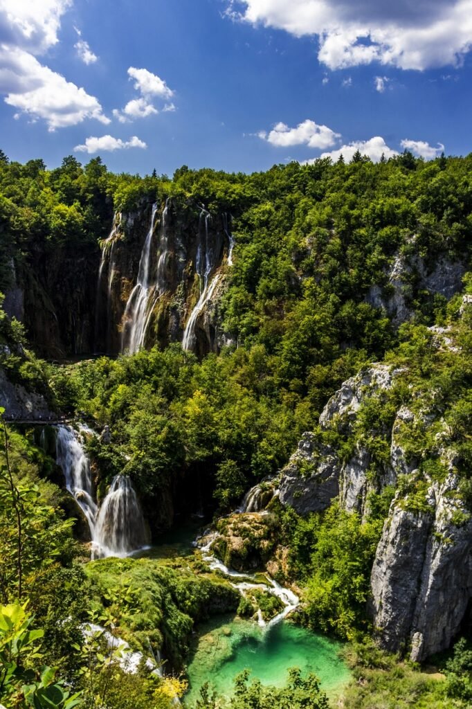 Fließende Wasserfälle und kaskadierende Seen im Nationalpark Plitvicer Seen, umgeben von dichtem Grün und Wald.