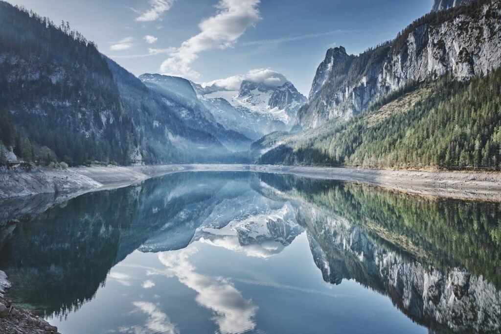 Ruhiger Bergsee im Salzkammergut, Oberösterreich, mit majestätischer Spiegelung der umliegenden Berge auf der Wasseroberfläche.