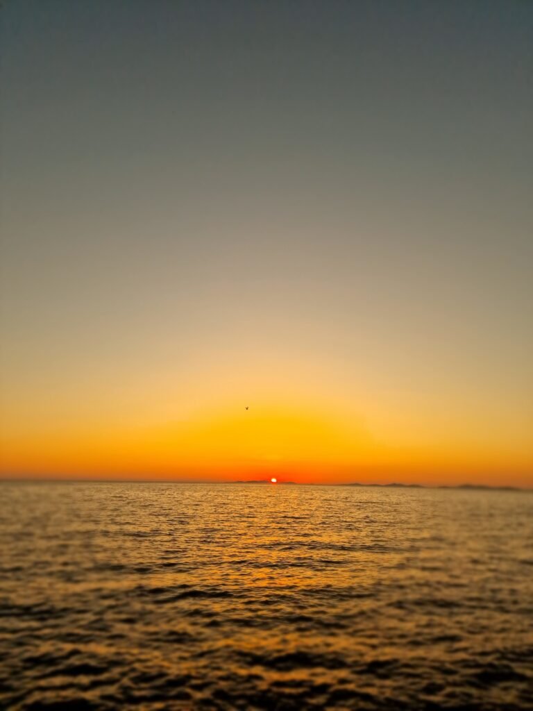 Spektakulärer Sonnenuntergang über dem Meer an der kroatischen Küste, mit leuchtenden Farben und Reflexionen im Wasser.